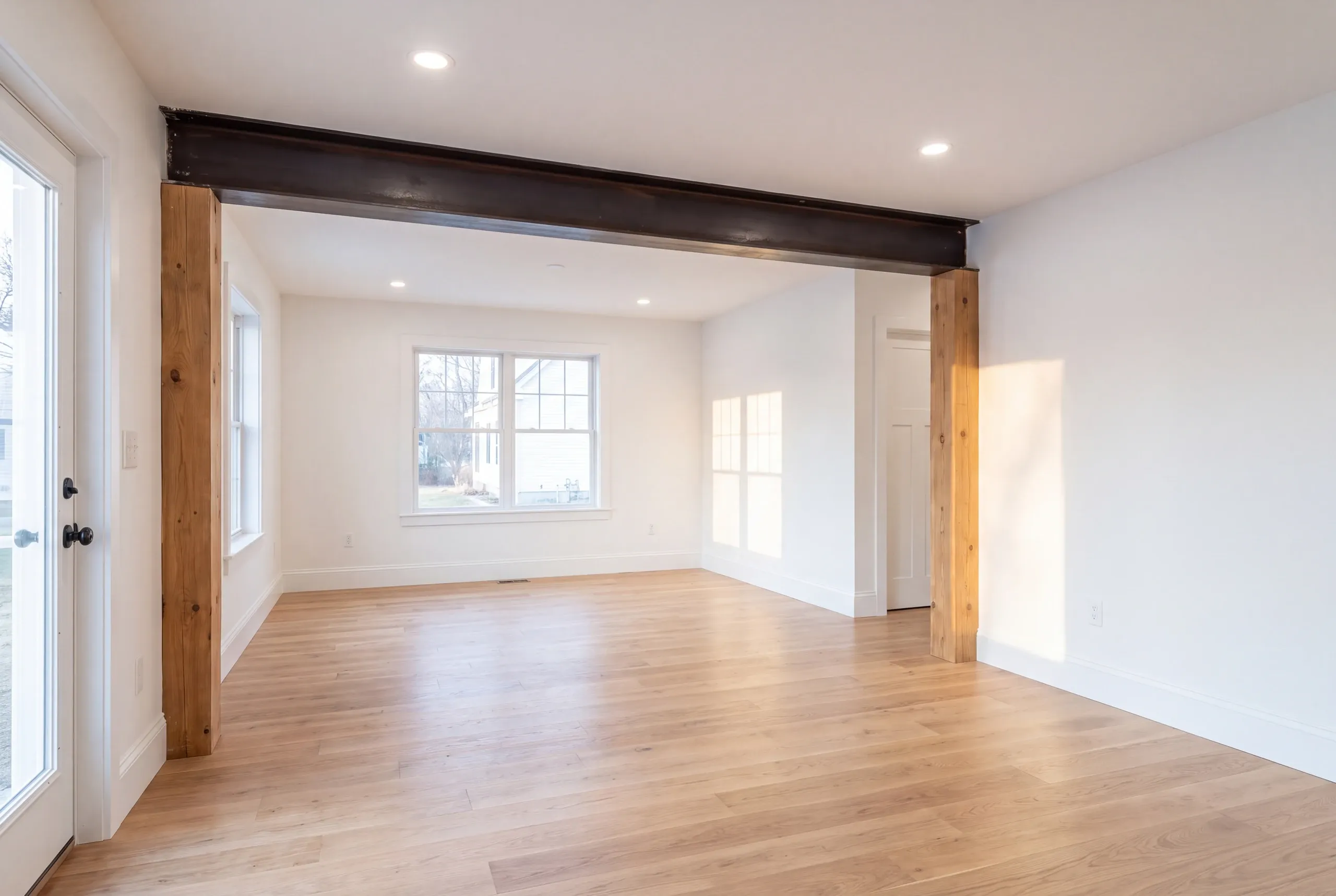 Cost to remodel a house in Augusta, ME: renovated open living room with a steel beam, wood posts and oak floors